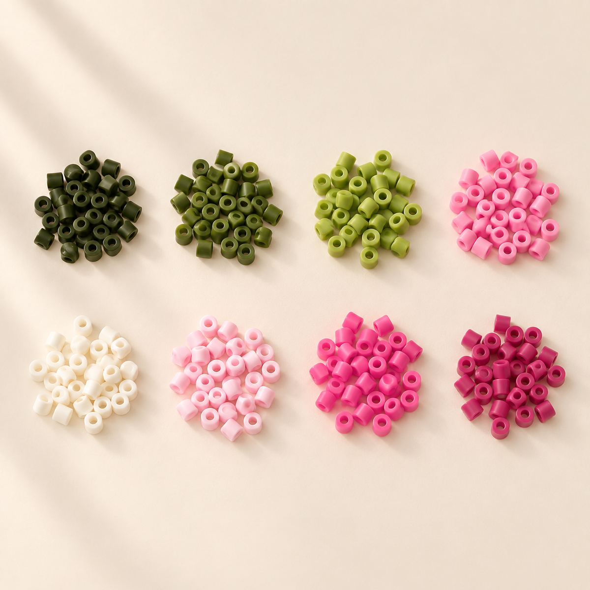 Eight small groups of representative green, ivory and pink fuse beads on a cream tabletop.