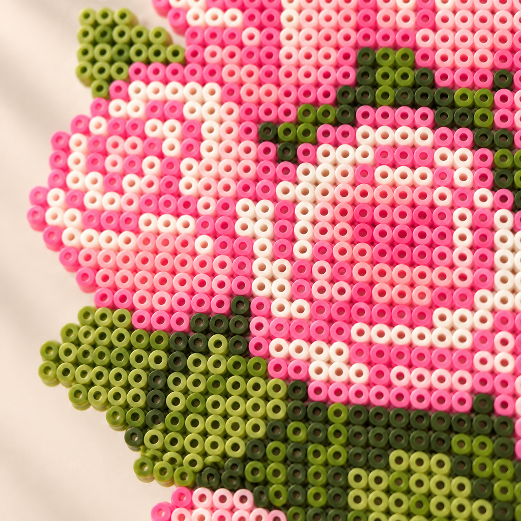 Close-up of pink rose and green leaf details in the fuse bead bouquet artwork.
